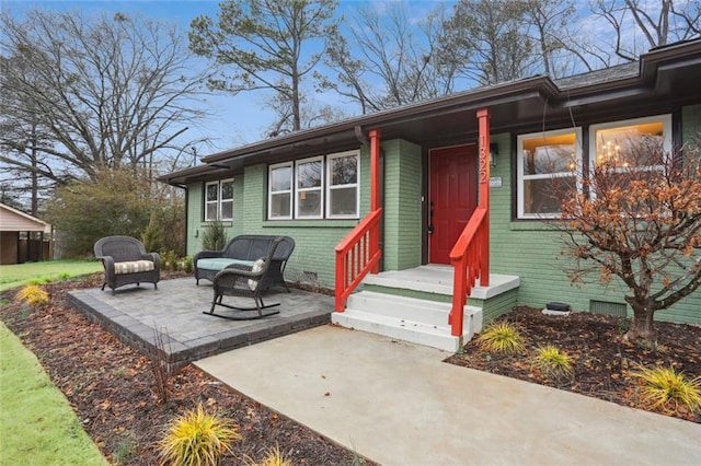 doorway to property featuring a patio, brick siding, crawl space, and outdoor lounge area