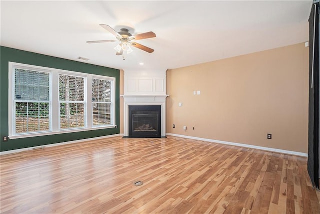 unfurnished living room with light hardwood / wood-style floors, ceiling fan, and a large fireplace