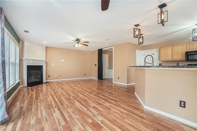 unfurnished living room featuring light wood-type flooring, ceiling fan, and a fireplace