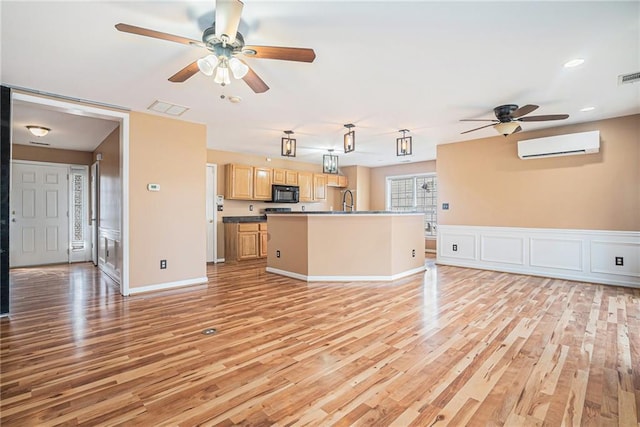 unfurnished living room featuring ceiling fan, sink, a wall unit AC, and light wood-type flooring