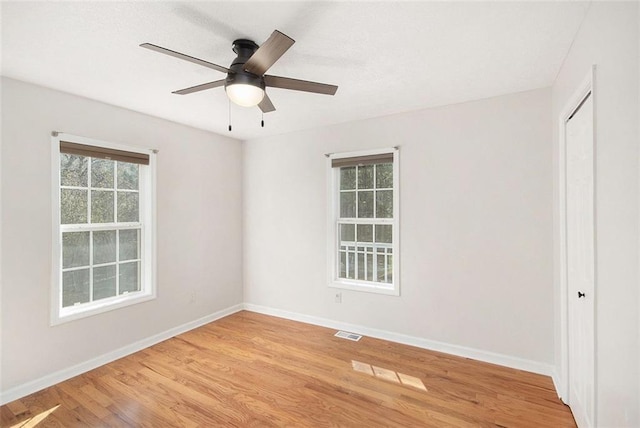 unfurnished room featuring baseboards, a ceiling fan, visible vents, and light wood-style floors