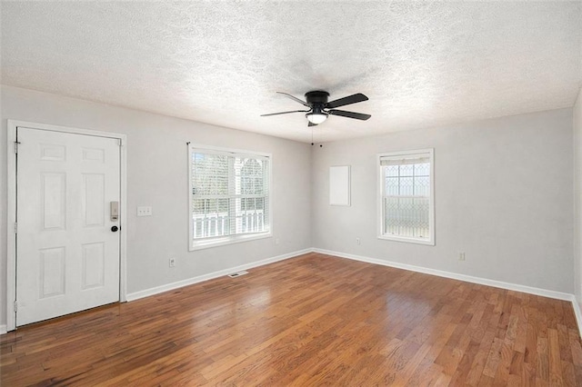 unfurnished room with visible vents, a ceiling fan, a textured ceiling, wood finished floors, and baseboards