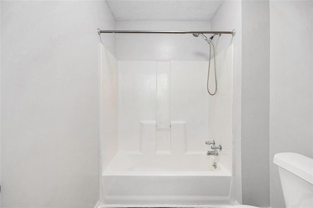 bathroom featuring shower / bath combination, a textured ceiling, and toilet