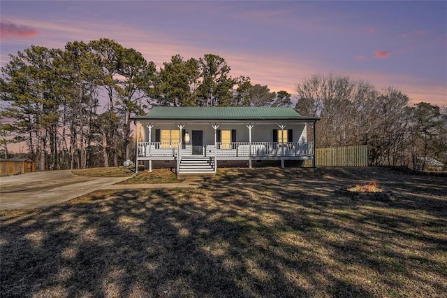 view of front of property featuring crawl space, covered porch, metal roof, and a yard