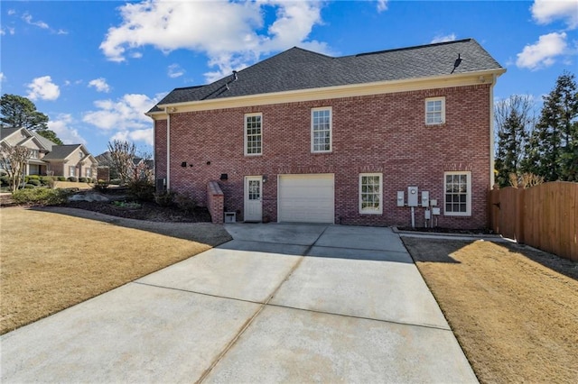 exterior space featuring a garage, concrete driveway, fence, a yard, and brick siding