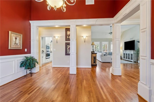 entryway with ceiling fan, light wood-type flooring, visible vents, and ornate columns