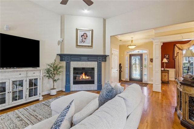 living room featuring plenty of natural light, ornamental molding, wood finished floors, and a tile fireplace