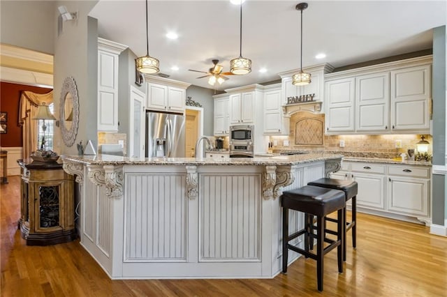 kitchen with appliances with stainless steel finishes, light wood-type flooring, a kitchen breakfast bar, and light stone countertops