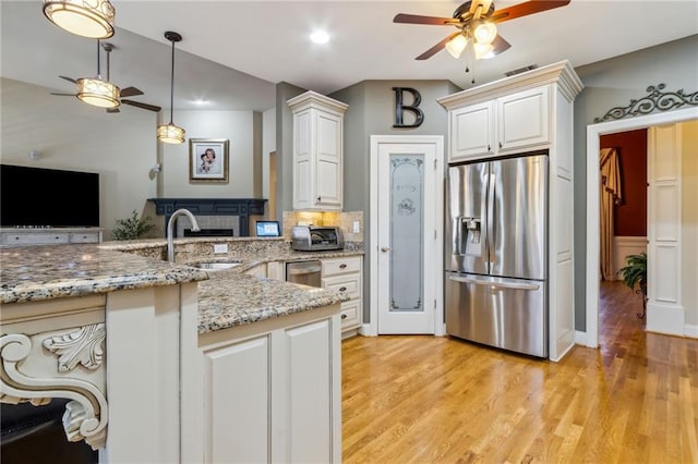 kitchen featuring visible vents, ceiling fan, light wood-type flooring, stainless steel refrigerator with ice dispenser, and a sink