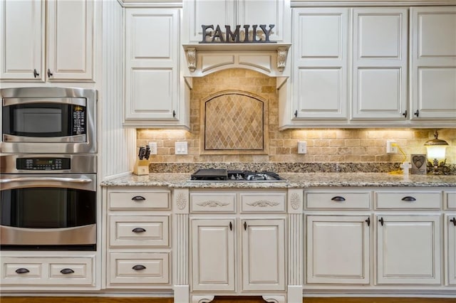 kitchen with white cabinets, light stone countertops, stainless steel appliances, and decorative backsplash