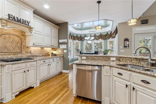 kitchen featuring a raised ceiling, light wood-style floors, a sink, gas cooktop, and dishwasher