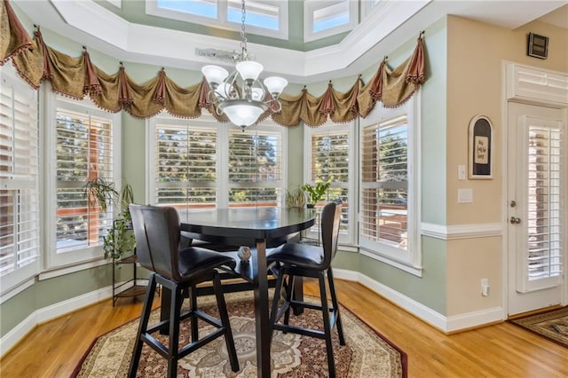 dining room with a wealth of natural light, light wood-style flooring, baseboards, and an inviting chandelier