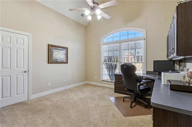 home office featuring ceiling fan, light carpet, visible vents, baseboards, and vaulted ceiling