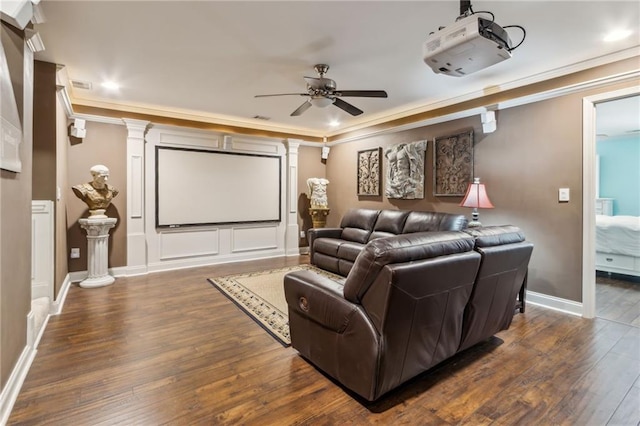 home theater featuring decorative columns, crown molding, baseboards, and wood finished floors