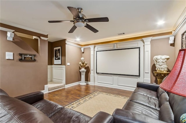 home theater featuring ornate columns, crown molding, visible vents, and wood finished floors