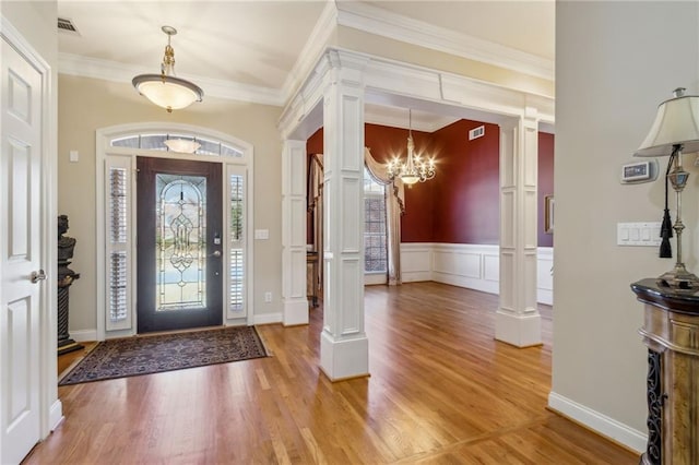 foyer entrance featuring light wood finished floors and decorative columns