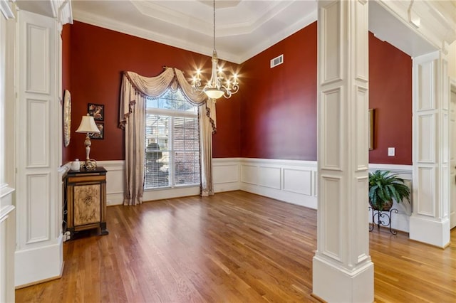 unfurnished dining area with light wood-type flooring, visible vents, ornate columns, and an inviting chandelier