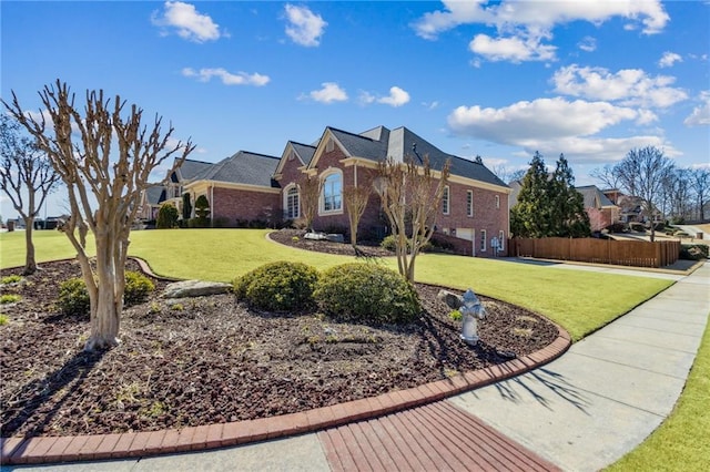 view of front of house featuring brick siding, fence, and a front lawn