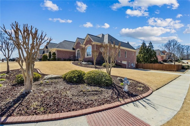 view of front of home featuring brick siding, a front yard, and fence