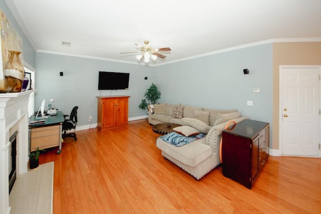 living area featuring ceiling fan, a fireplace, baseboards, light wood-style floors, and ornamental molding