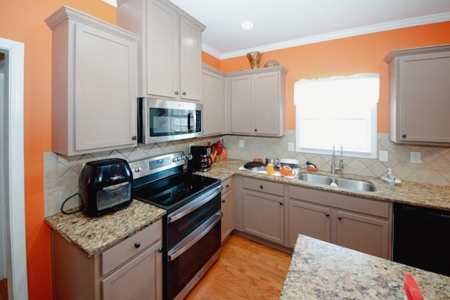 kitchen featuring light wood finished floors, appliances with stainless steel finishes, a sink, crown molding, and backsplash