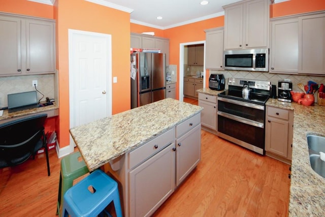 kitchen featuring appliances with stainless steel finishes, a center island, ornamental molding, and light wood finished floors