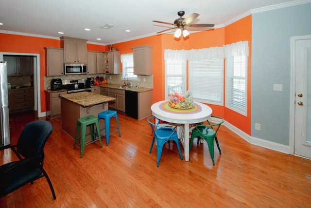 kitchen with stainless steel appliances, light wood-style floors, ornamental molding, and a kitchen island