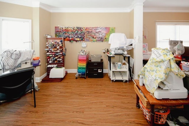 interior space featuring light wood-style floors, baseboards, ornamental molding, and ornate columns