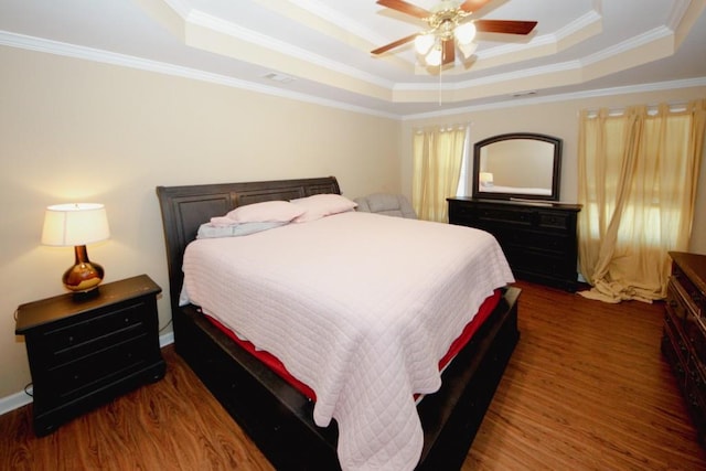 bedroom featuring ornamental molding, ceiling fan, a tray ceiling, and wood finished floors