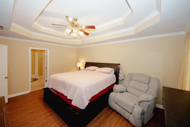 bedroom featuring ornamental molding, wood finished floors, a raised ceiling, and baseboards