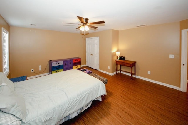 bedroom featuring a ceiling fan, visible vents, baseboards, and wood finished floors