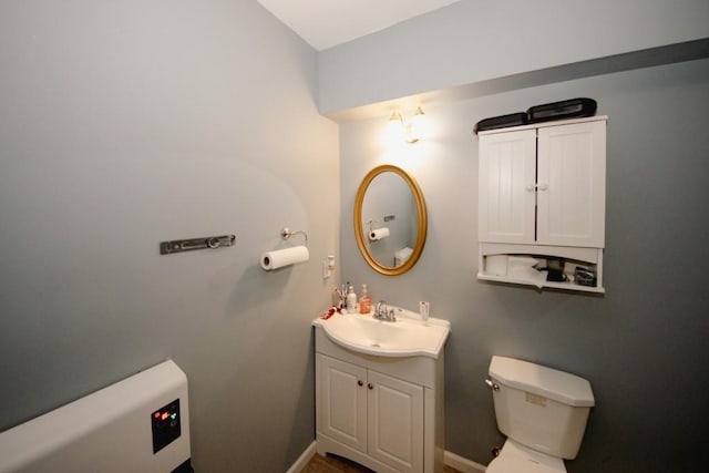 half bathroom with vanity, toilet, and baseboards