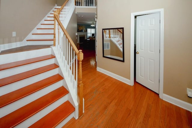 stairway with a fireplace, baseboards, and wood finished floors