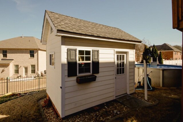 view of outbuilding featuring a fenced in pool, fence, and an outdoor structure