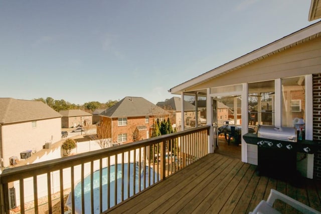 deck with grilling area, a residential view, and a fenced in pool