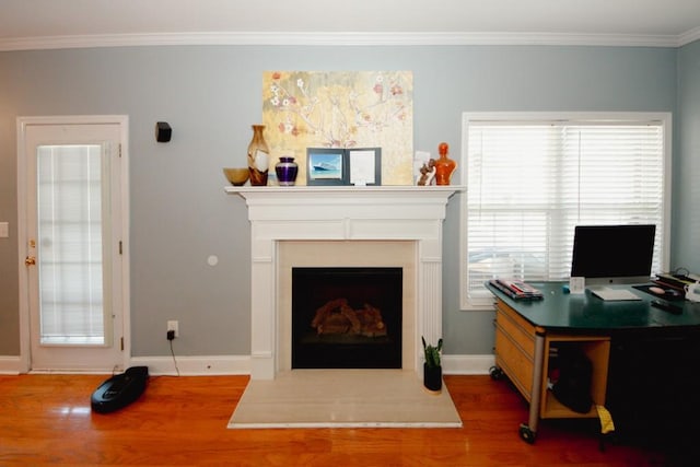 living room featuring ornamental molding, a fireplace with raised hearth, baseboards, and wood finished floors