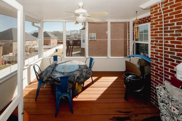 sunroom / solarium featuring a residential view and a ceiling fan