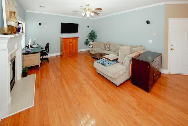 living area featuring baseboards, a fireplace with raised hearth, ceiling fan, ornamental molding, and light wood-type flooring