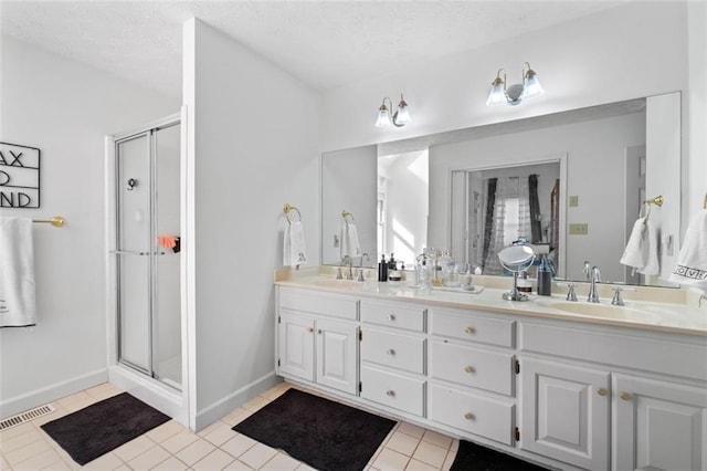 bathroom with a stall shower, visible vents, a sink, and double vanity