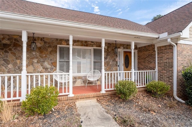 property entrance featuring stone siding, roof with shingles, and brick siding