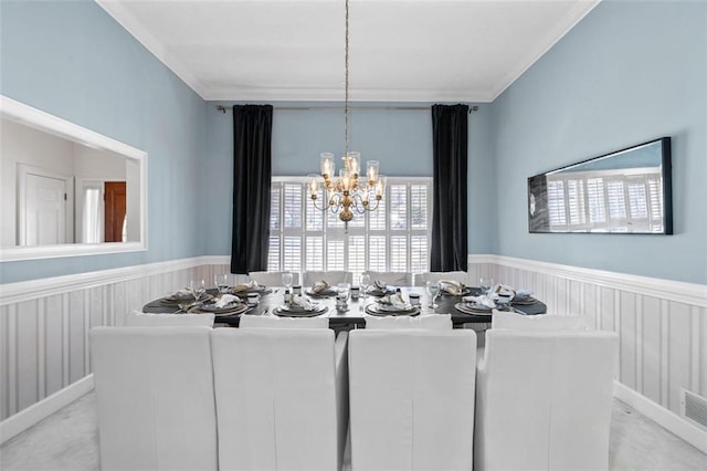 dining area featuring crown molding, wainscoting, a notable chandelier, and light carpet