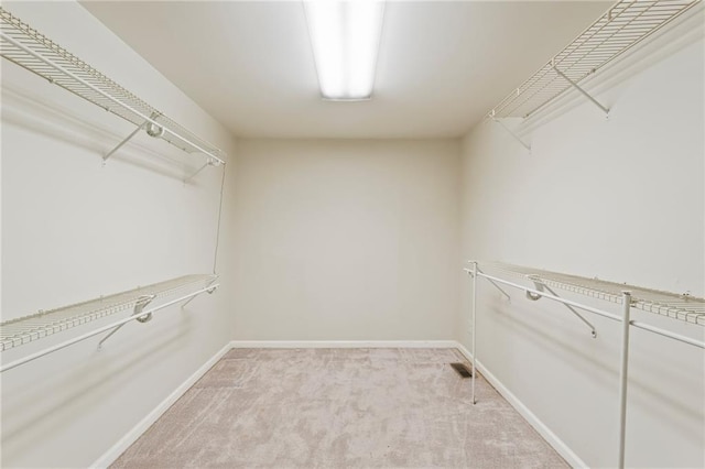 walk in closet featuring light colored carpet