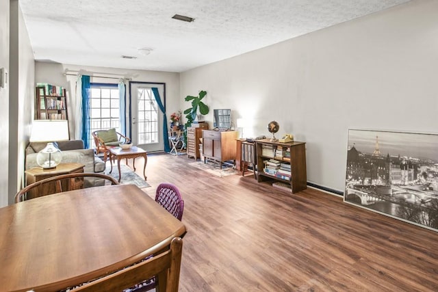 dining space featuring wood-type flooring and a textured ceiling