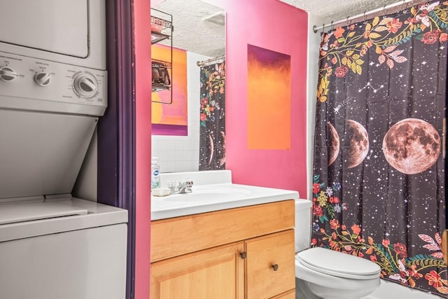 bathroom featuring vanity, toilet, a textured ceiling, and stacked washer / dryer