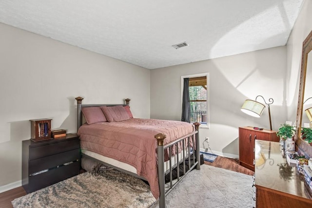 bedroom with wood-type flooring and a textured ceiling