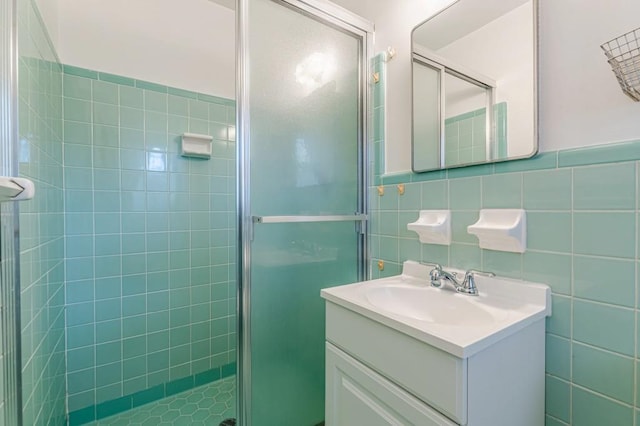 bathroom with vanity, an enclosed shower, and tile walls