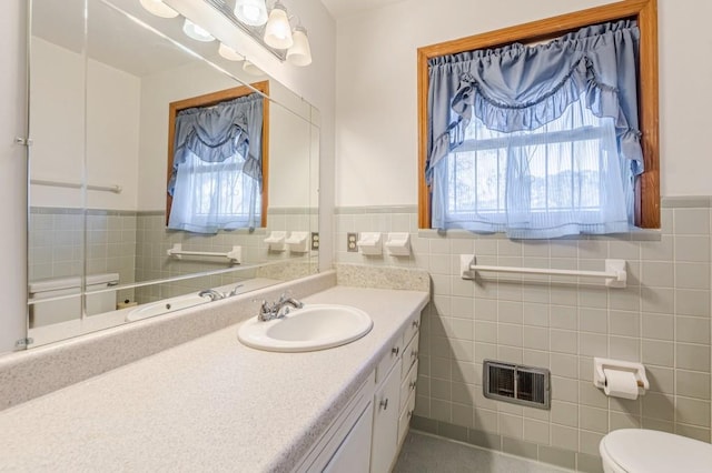 bathroom with vanity, toilet, tile walls, and a wealth of natural light