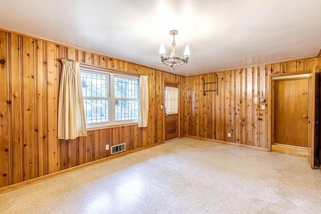 empty room featuring wooden walls and a chandelier