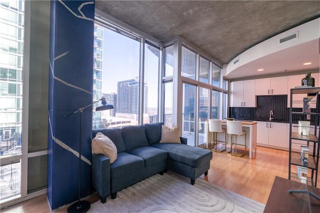 living room with a wall of windows, a view of city, light wood-style flooring, and visible vents