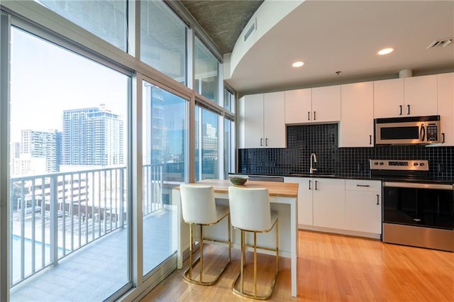 kitchen with a sink, stainless steel appliances, visible vents, and a wealth of natural light